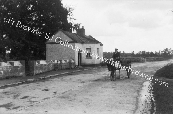 MAN ON DONKEY CART PASSING TOLL HOUSE